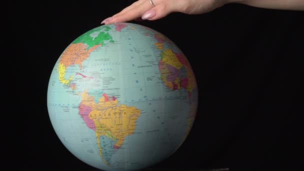 Географический глобус вращается вокруг своей оси женской рукой — стоковое видео