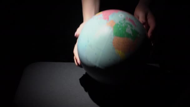 Las manos de las niñas tuercen el globo geográfico alrededor de su eje — Vídeo de stock