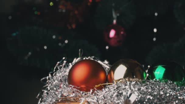Нові роки іграшки лежать на блискучій крихітці всупереч притчі Різдвяного дерева. — стокове відео