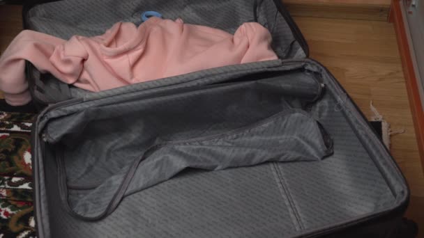 Fille recueille des vêtements dans une valise — Video