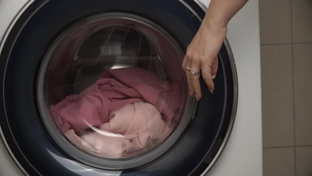 Vrouwen handen zetten kleren in een moderne wasmachine — Stockvideo