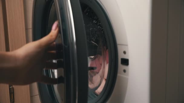 Női kéz tegye ruhák egy modern mosógép — Stock videók