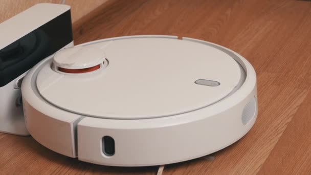 Aspirateur robotique blanc commence le nettoyage de sa station de charge — Video