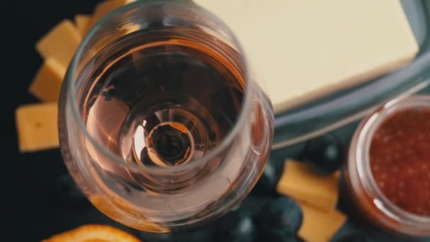 Ένα ποτήρι ροζέ κρασί στροβιλίζεται με ορεκτικά — Αρχείο Βίντεο