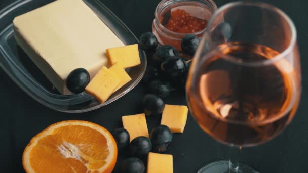 Niña toma uvas contra el fondo de una copa de vino y aperitivos — Vídeos de Stock