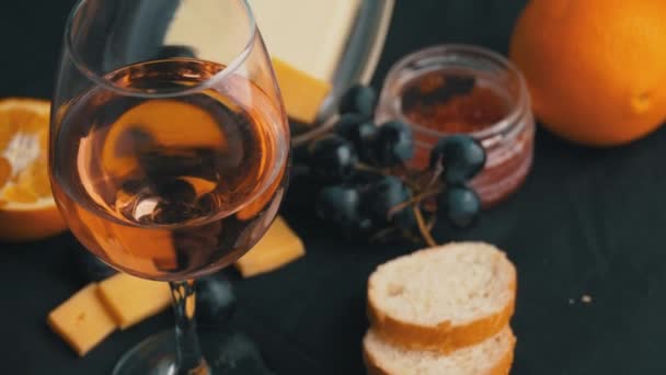 Szklanka różowego wina wiruje z przekąskami — Wideo stockowe