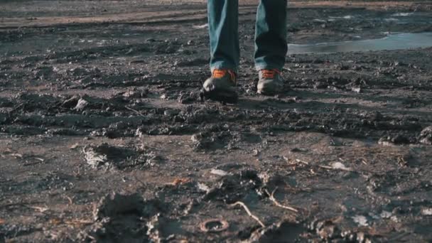 Hombre con botas camina a través del barro, salpicando desde un charco en Slowmo — Vídeo de stock