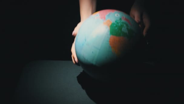 Las manos de las niñas tuercen el globo geográfico alrededor de su eje — Vídeo de stock