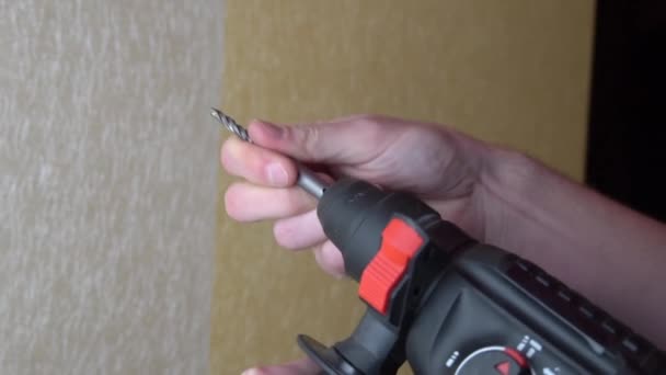 Мужские руки сверлить отверстие в стене с обоями сверла — стоковое видео
