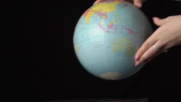 Globo geográfico é torcido em torno de seu eixo por uma mão feminina — Vídeo de Stock