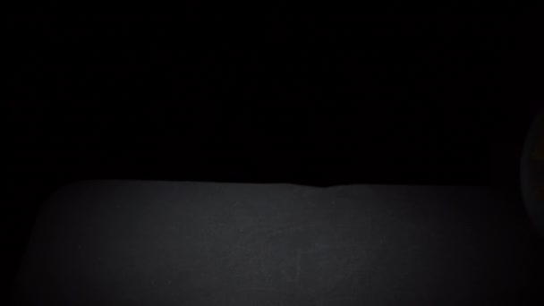 Rolos de globo geográfico em uma superfície preta em Slowmo — Vídeo de Stock