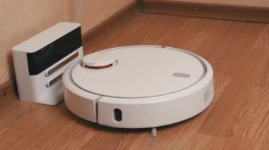 Beyaz Robotik Elektrikli Süpürge Temizleyicisi Temizliği bitirdi ve Şarj İstasyonuna Sürüyor