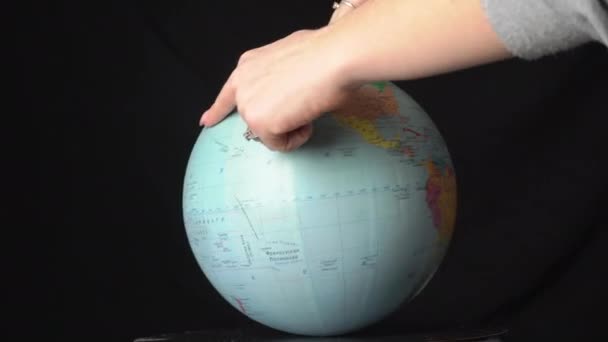 Geografische bol is gedraaid rond zijn as door een vrouwelijke hand — Stockvideo