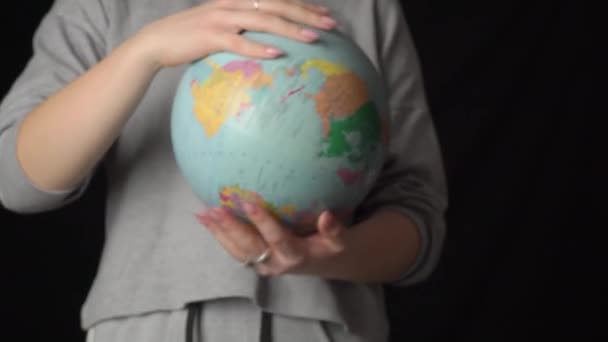 女の子の手は、その軸の周りの地理的な球をねじる — ストック動画
