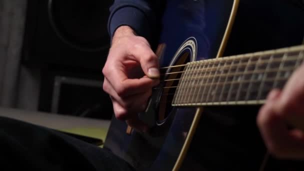 De mens speelt een plectrum op een moderne gitaar in de donkere trage ma — Stockvideo