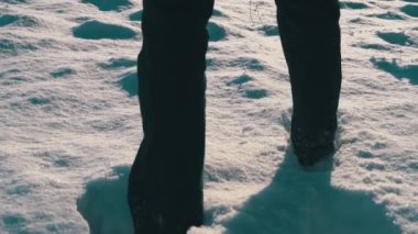 Kar yığınlarının arasından bir adam sızar.