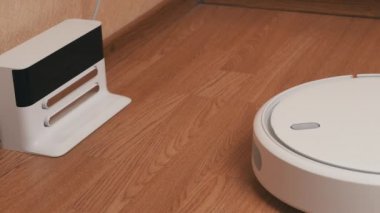 Beyaz Robotik Elektrikli Süpürge Temizleyicisi Temizliği bitirdi ve Şarj İstasyonuna Sürüyor