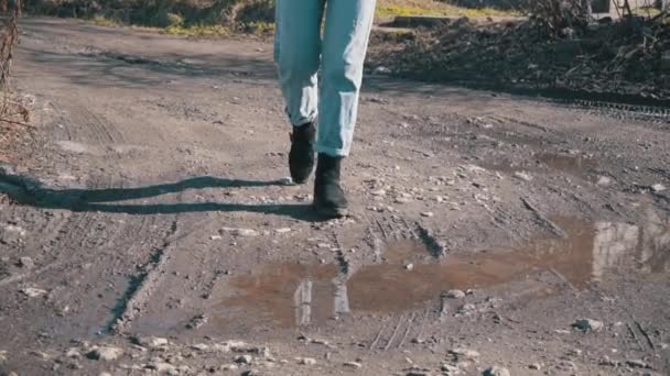 Ragazza in Jeans cammina attraverso il fango in lenta Mo — Video Stock