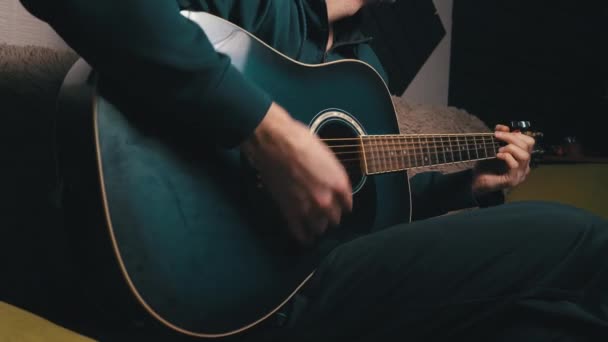 De mens speelt een plectrum op een moderne gitaar in het donker — Stockvideo