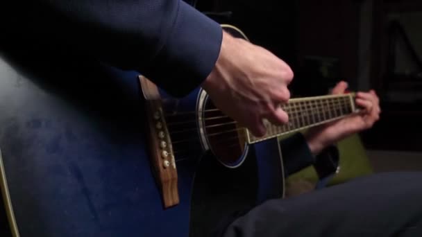 De mens speelt een plectrum op een moderne gitaar in de donkere trage ma — Stockvideo