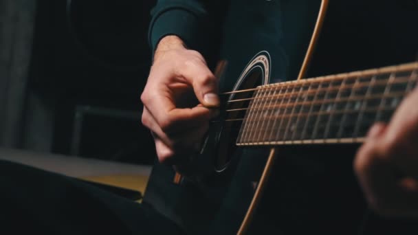 De mens speelt een plectrum op een moderne gitaar in de donkere trage ma — Stockvideo