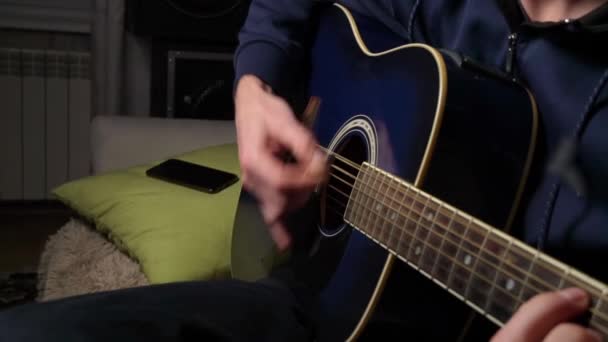 De mens speelt een plectrum op een moderne gitaar in de donkere trage ma — Stockvideo