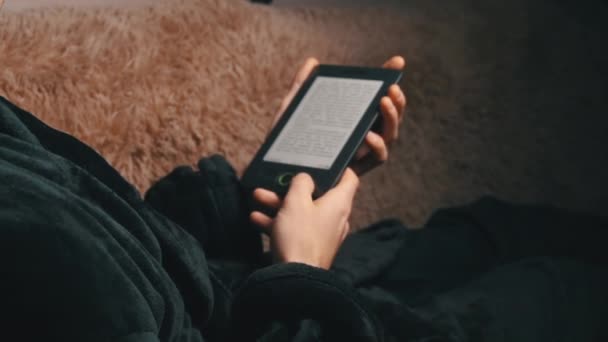 L'uomo in accappatoio legge un e-book mentre si siede sul divano — Video Stock