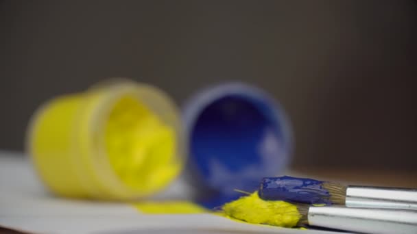 Toman pintura amarilla y azul con un pincel, Ucrania — Vídeo de stock