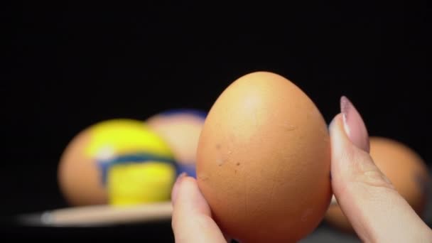 Dívka maluje velikonoční vejce v žlutomodré barvě — Stock video
