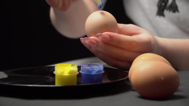 Niña pinta huevos de Pascua en color amarillo-azul — Vídeo de stock