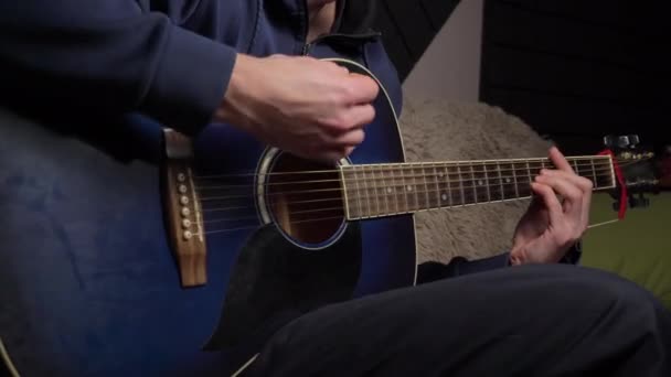 De mens speelt een plectrum op een moderne gitaar in het donker — Stockvideo