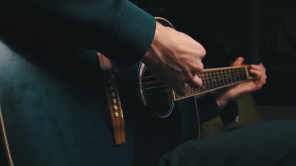 De mens speelt een plectrum op een moderne gitaar in de donkere trage ma — Stockvideo