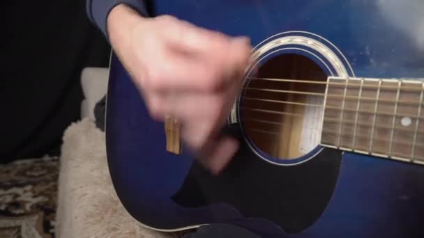 Mann spielt Akustikgitarre im Sitzen auf Couch — Stockvideo