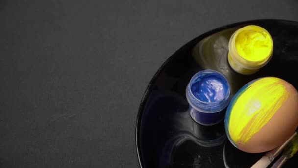 Meisje verft paaseieren in geel-blauwe kleur — Stockvideo