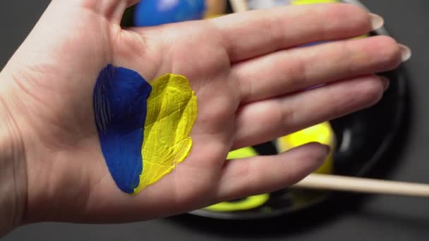 Pomalowana żeńska ręka w żółto-niebieskim kolorze na tle pisanek — Wideo stockowe