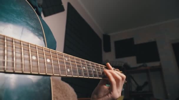 Muž hraje na akustickou kytaru, zatímco sedí na gauči — Stock video