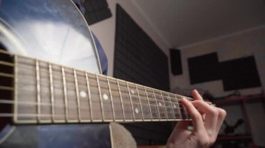 Adam koltukta otururken akustik gitar çalıyor.