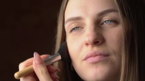 Visage d'une belle jeune femme appliquant la blush avec un pinceau sur son visage — Video