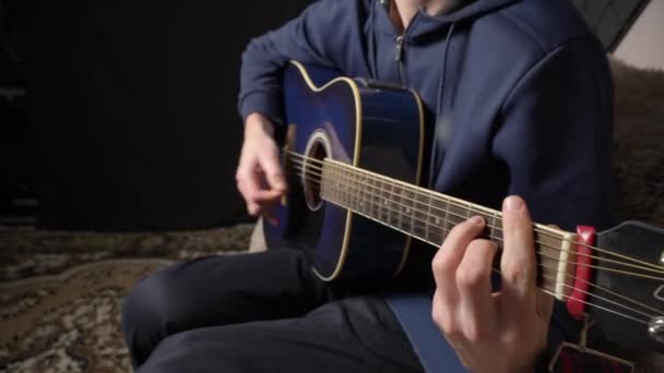 Muž hraje na akustickou kytaru, zatímco sedí na gauči — Stock video
