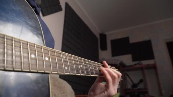 Mannen spelar en akustisk gitarr medan han sitter på en soffa — Stockvideo