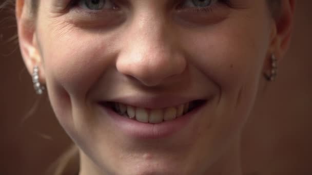 Обличчя красивої молодої жінки дивиться і посміхається на камеру — стокове відео