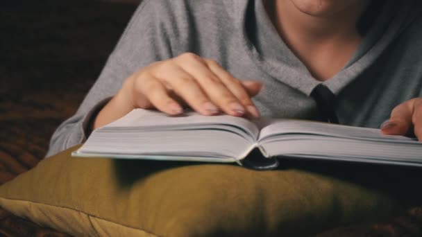 Söt flicka läser och blad genom en bok medan du ligger bekvämt i sängen — Stockvideo