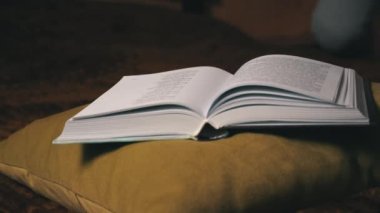 Sevimli kız, yatakta rahat bir şekilde yatarken kitap okuyup sayfalarını karıştırıyor.