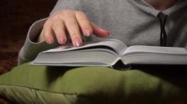 Güzel kız yatakta yatarken rahatça kitap okur.