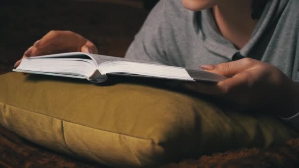 Söt flicka läser och blad genom en bok medan du ligger bekvämt i sängen — Stockvideo