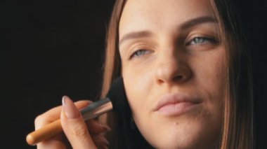 Yüzünde bir fırçayla allık süren güzel genç bir kadının yüzü