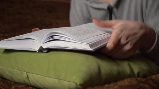 Красива дівчина читає книгу зручно лежачи в ліжку — стокове відео