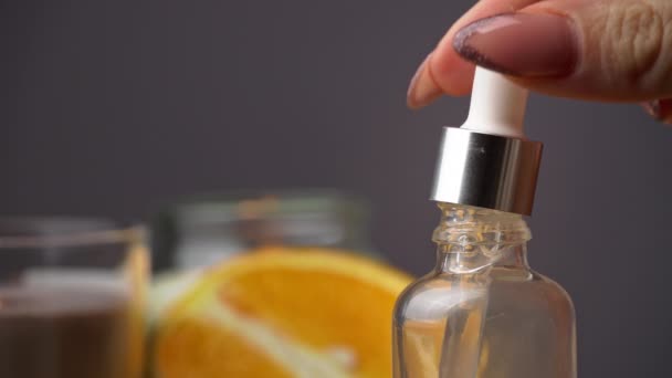 El aceite esencial gotea de una pipeta en una botella sobre el fondo de una vela — Vídeo de stock