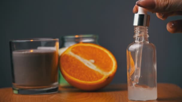 Ätherisches Öl tropft von einer Pipette in eine Flasche auf dem Hintergrund einer Kerze — Stockvideo