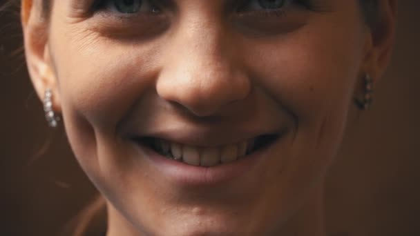Ansiktet på en vacker ung kvinna tittar och ler mot kameran — Stockvideo